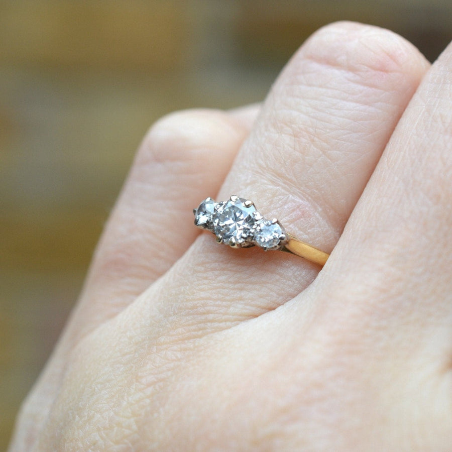 Art Deco 18ct gold three stone diamond ring on hand, featuring a central transitional cut diamond with two smaller diamonds.