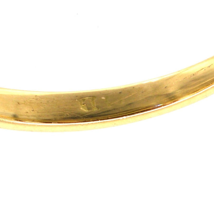 Close-up of the inner band of a gold ring showcasing hallmark details.
