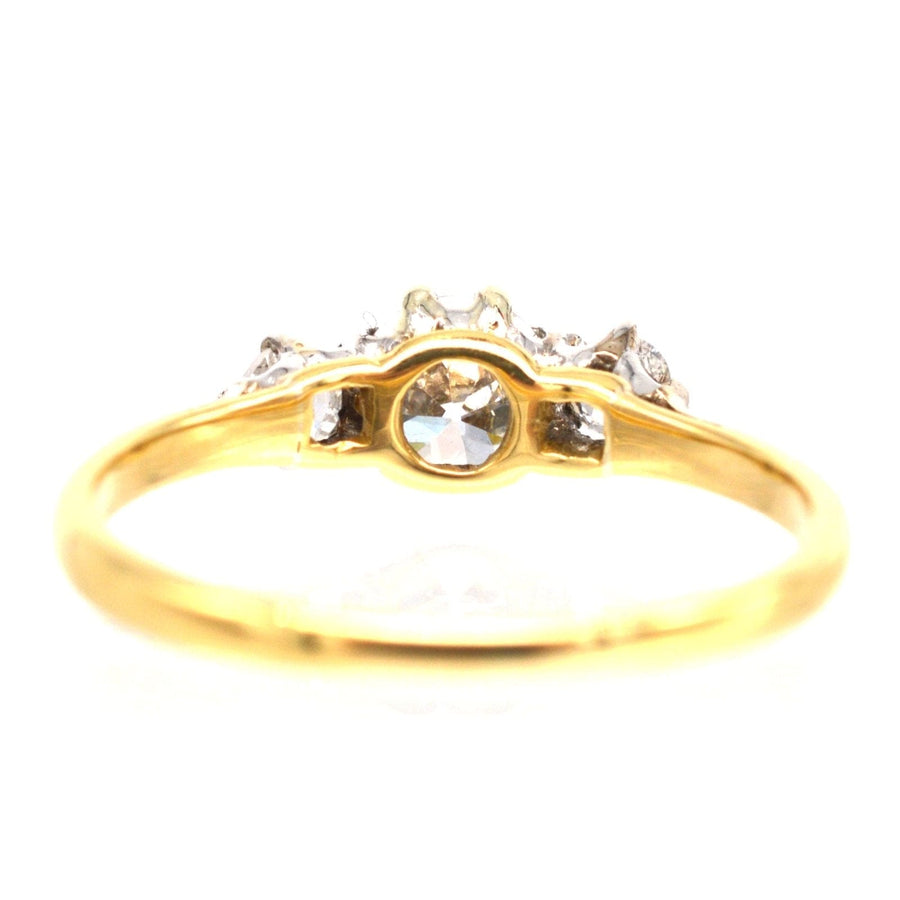 Art Deco 18ct gold three stone diamond ring featuring a central transitional cut diamond and two smaller diamonds.
