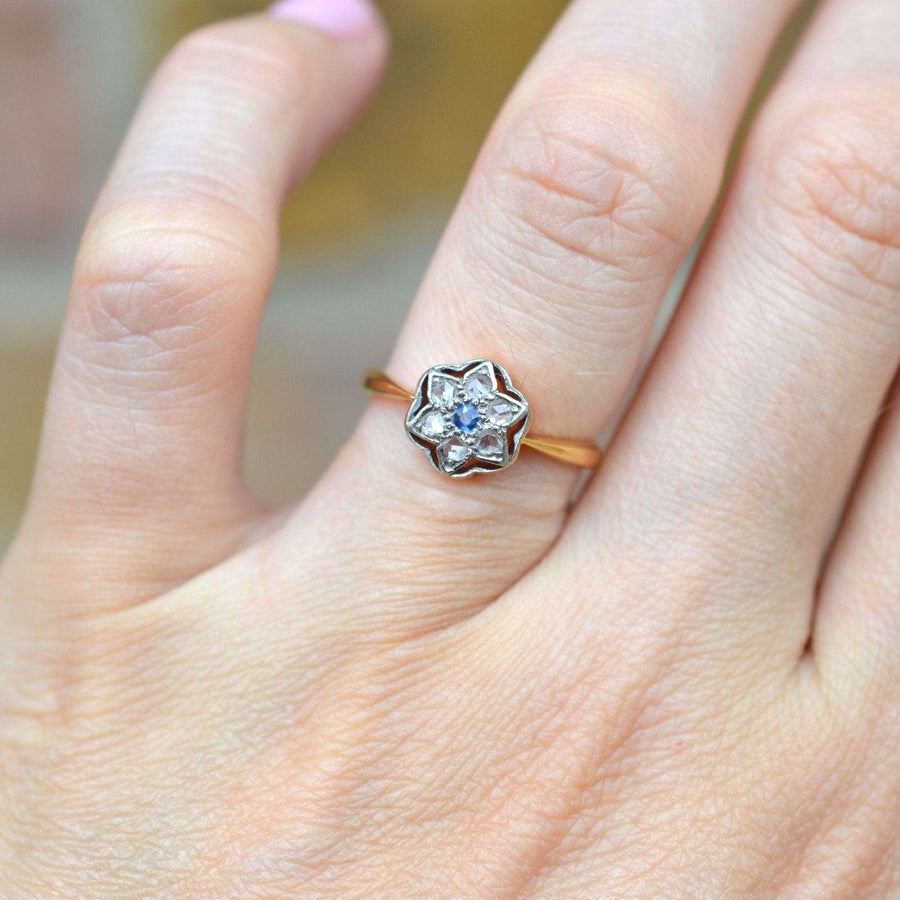 Art Deco 18ct & Platinum diamond and sapphire flower star ring displayed on a woman's hand.