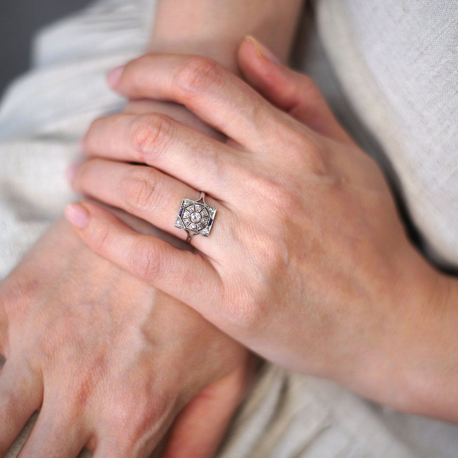 Art Deco 18ct white gold and platinum diamond and sapphire plaque ring worn on a hand, showcasing its geometric design.