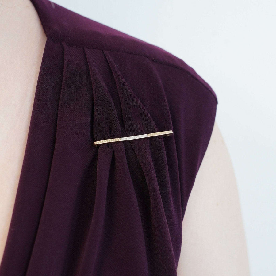 Art Deco 9ct gold and platinum engine turned bar brooch on a purple dress.