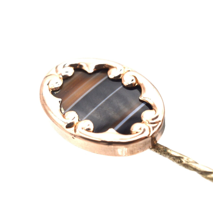 Edwardian 9ct gold banded sardonyx agate tie pin with ornate swirl frame, circa 1910.