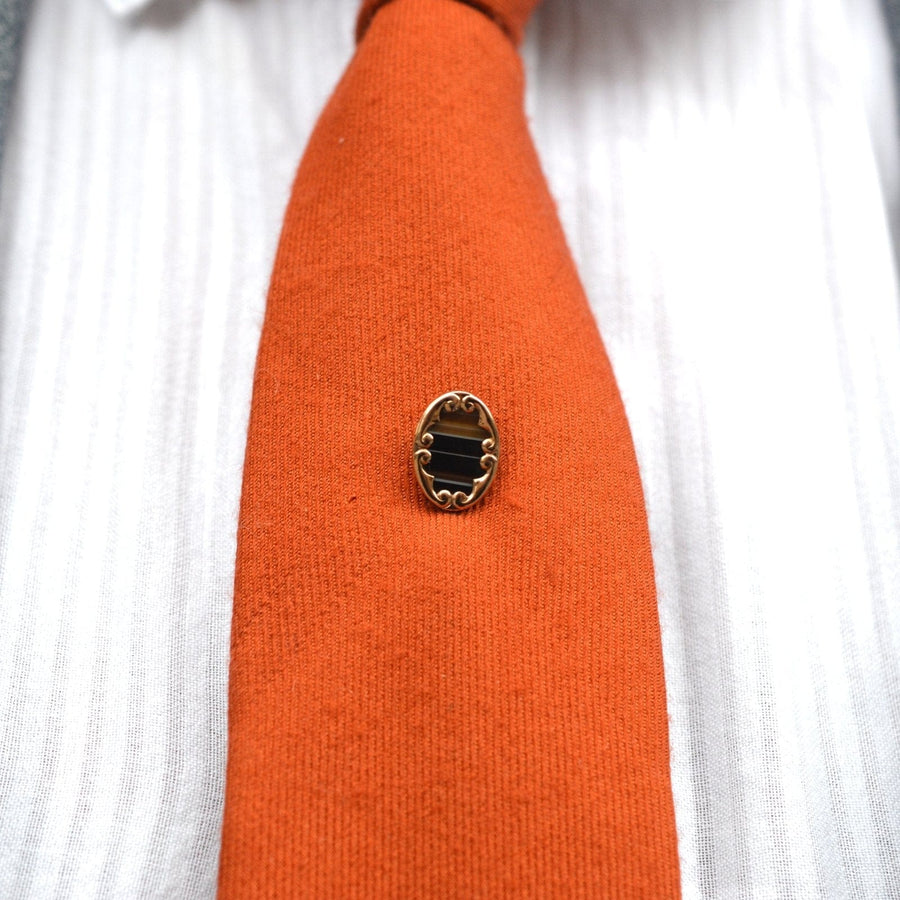 Edwardian 9ct gold sardonyx agate tie pin on an orange silk tie, showcasing vintage elegance and style.