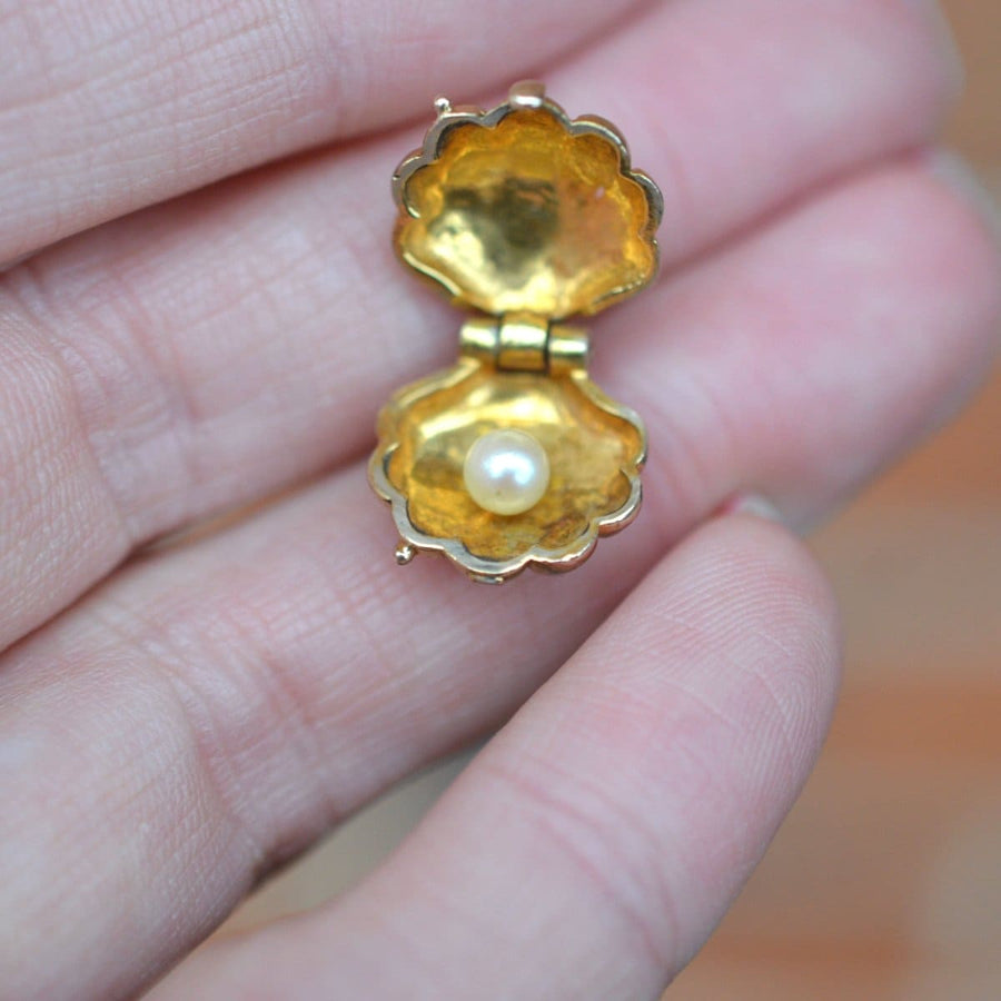 Vintage 9ct gold scallop shell charm pendant with pearl, opened in hand, showcasing intricate design.