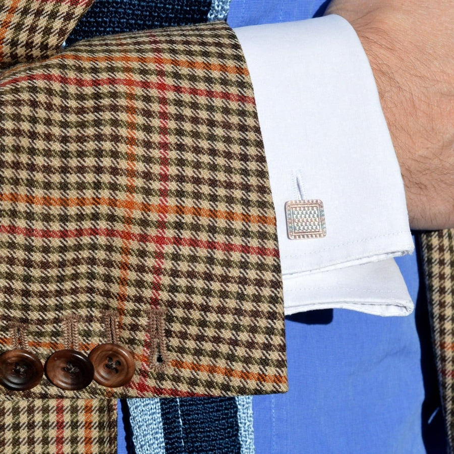 Close-up of a stylish cuff with Art Deco two-colour gold cufflinks on a patterned jacket sleeve.