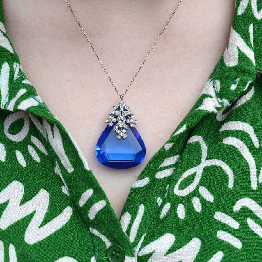 Elegant Art Deco chrome blue pendant on silver chain, adorned with white paste floral detailing.