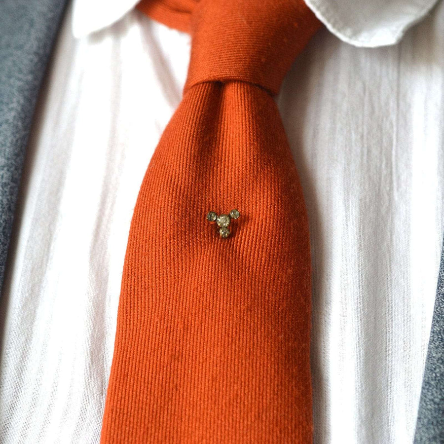 Art Deco gilt metal paste trio tie pin on an orange silk tie, adding a stylish touch to the outfit.