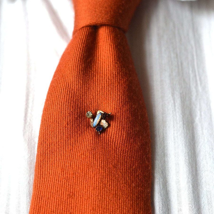 Art Deco Isle of Mann Triskelion Paste Tie Pin on an orange tie, featuring blue, red, white, and opal stones.