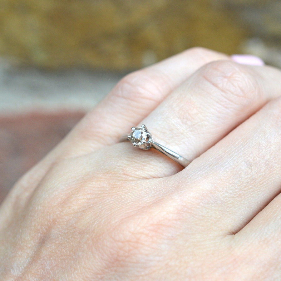 Art Deco platinum ring featuring a solitaire cognac diamond, elegantly displayed on a hand.