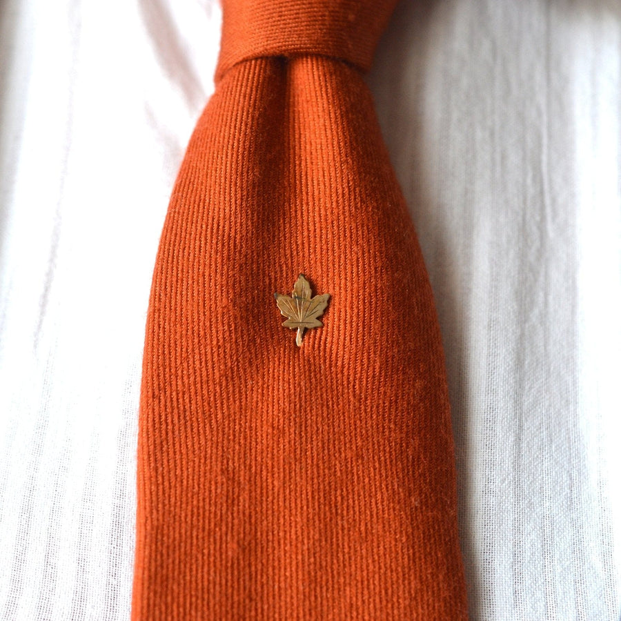 Art Deco rolled gold plate maple leaf tie pin on an orange tie, symbolizing Canada and Celtic mythology.