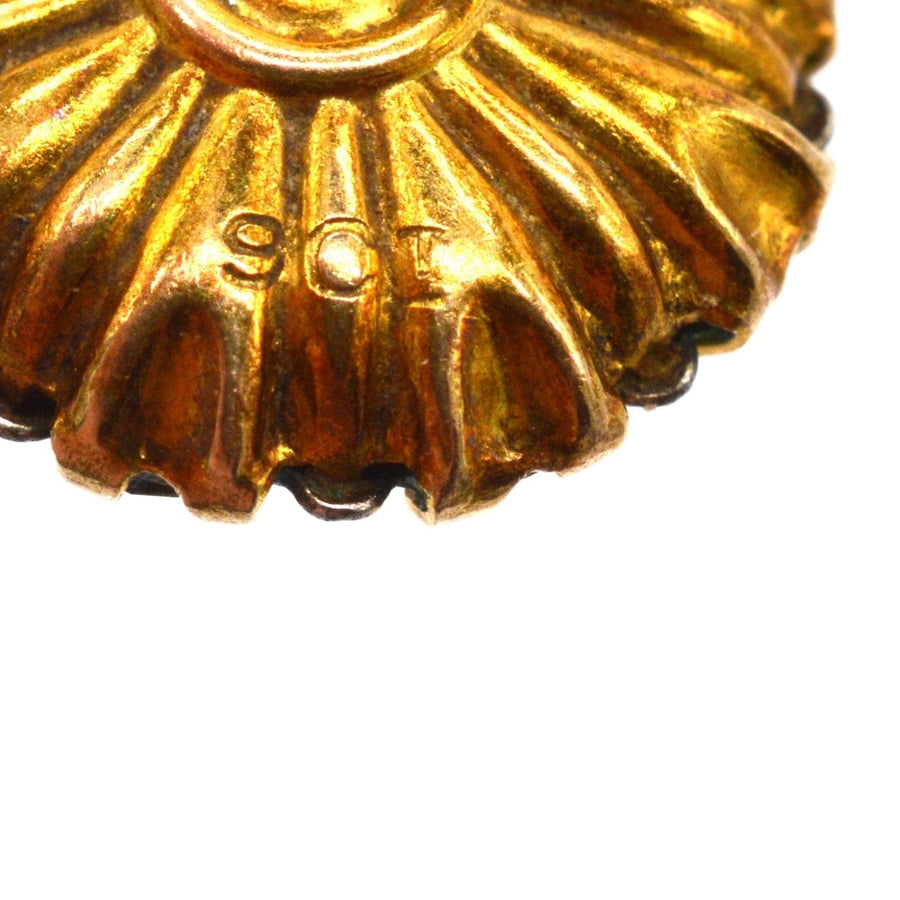 Close-up of 9ct gold hallmark on decorative Art Deco earring design with radiant texture.