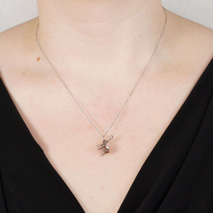 Art Deco silver Thonet bistro chair charm pendant on a delicate necklace worn by a model.