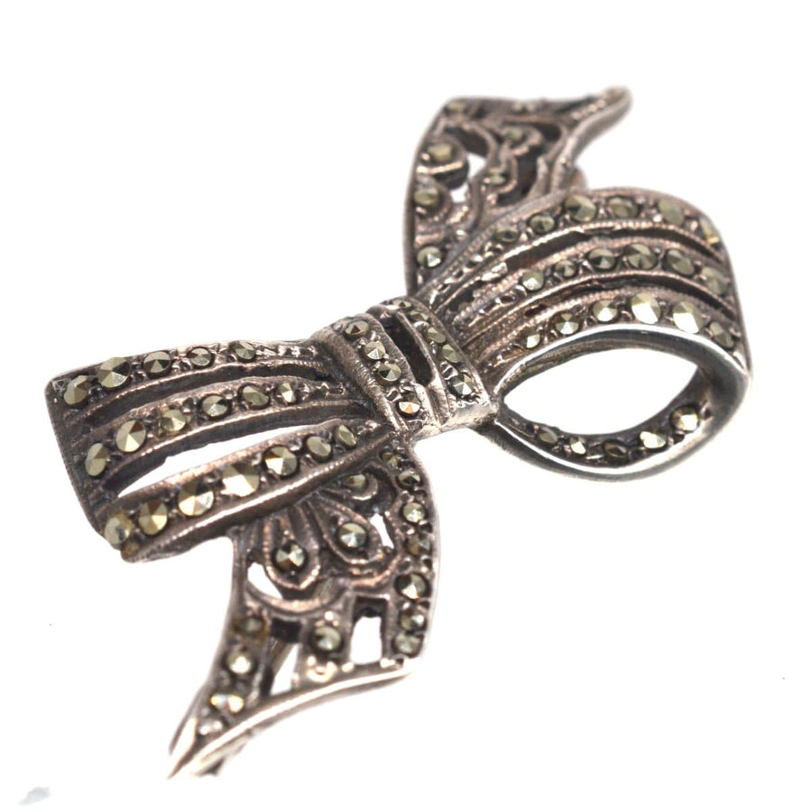Art Deco silver bow brooch with marcasite accents, vintage 1920s design, elegant jewelry piece.