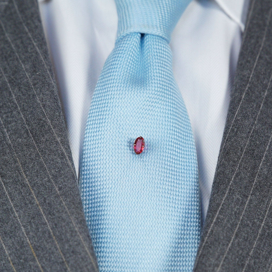Art Deco silver tie pin with red paste on a light blue silk tie, vintage 1920s costume jewelry.