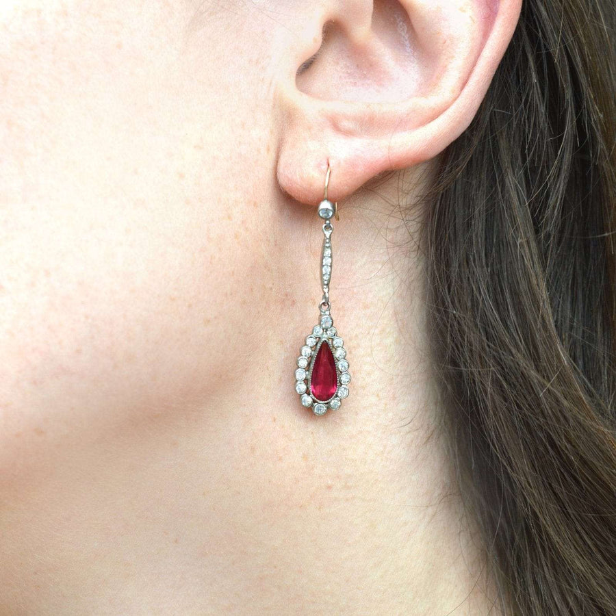 Art Deco silver-tone cluster drop earrings featuring a red 'ruby' paste in a pear shape, worn elegantly.
