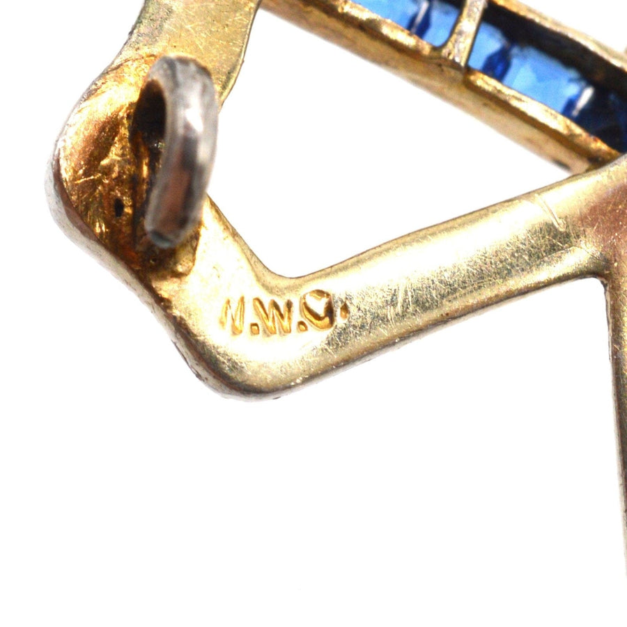 Close-up view of the hallmark on an Art Deco brooch featuring blue sapphire paste and gold detailing.