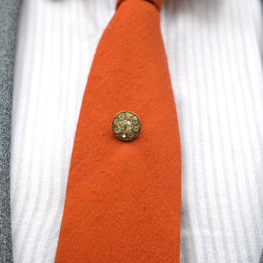Art Deco white paste cluster tie pin on an orange silk tie, showcasing a classic and stylish design.