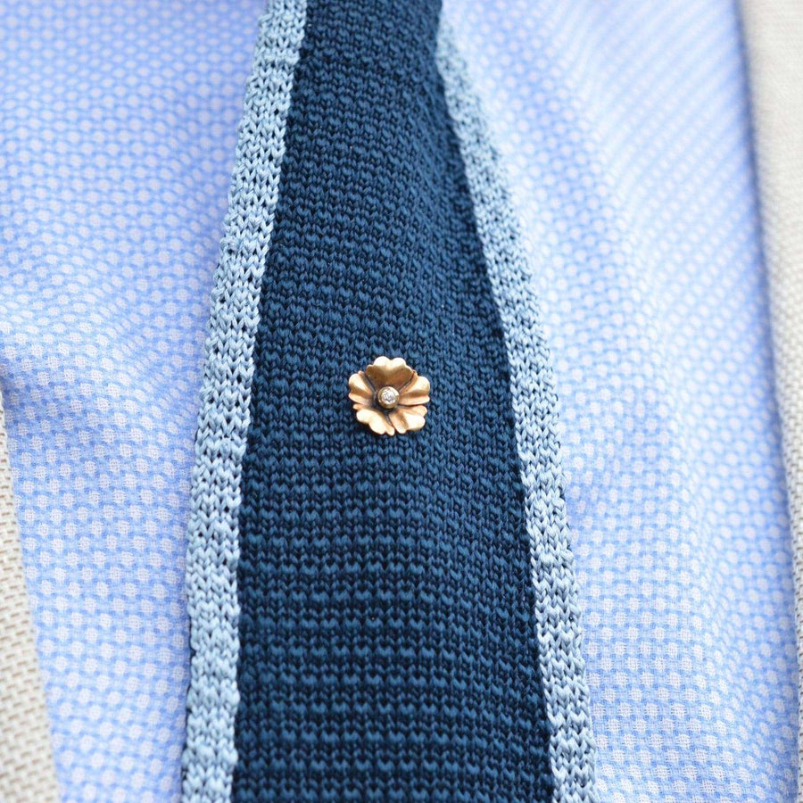 Art Nouveau 9ct gold flower tie pin adorning a textured blue tie, styled for elegance and charm.