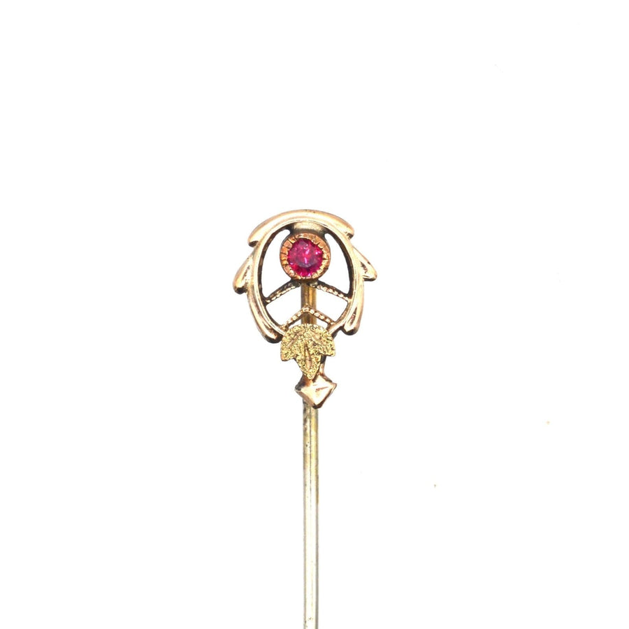 Art Nouveau tie pin in two-tone gold with ruby, featuring stylized leaves and millegrain setting for stylish elegance.
