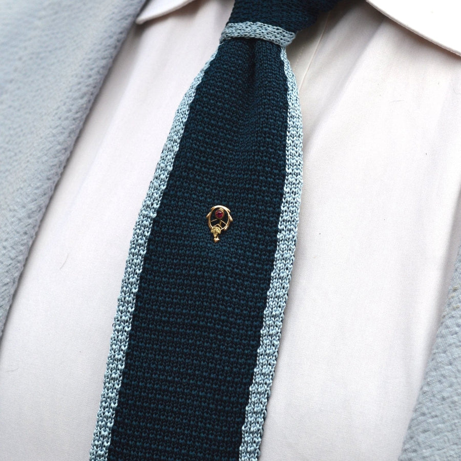 Art Nouveau 9ct gold and ruby tie pin displayed on a dark green and light blue silk tie.