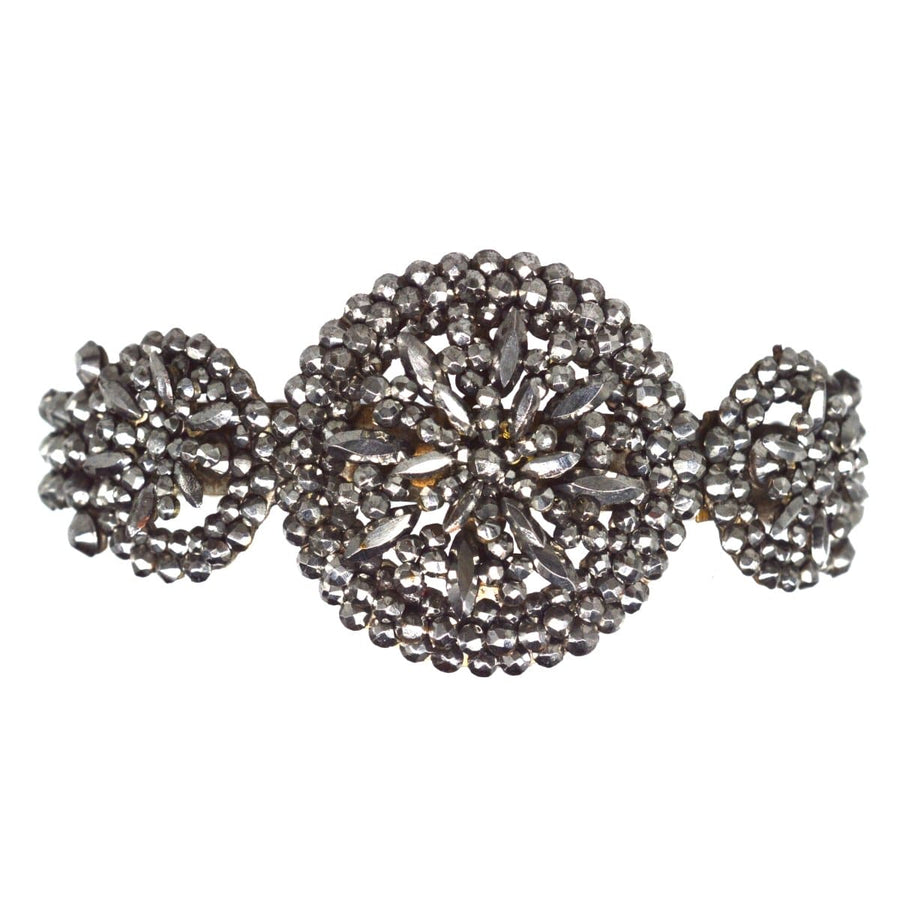 Early 19th Century cut steel bangle with intricate floral design, sparkling under candlelight.