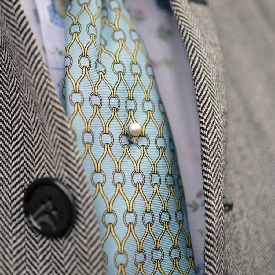 Elegant Edwardian 14ct gold tie pin featuring a natural pearl and diamond, styled on a blue patterned silk tie.