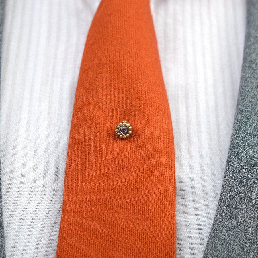 Elegant Edwardian 15ct gold stickpin featuring amethyst and pearl cluster on a vibrant orange tie.