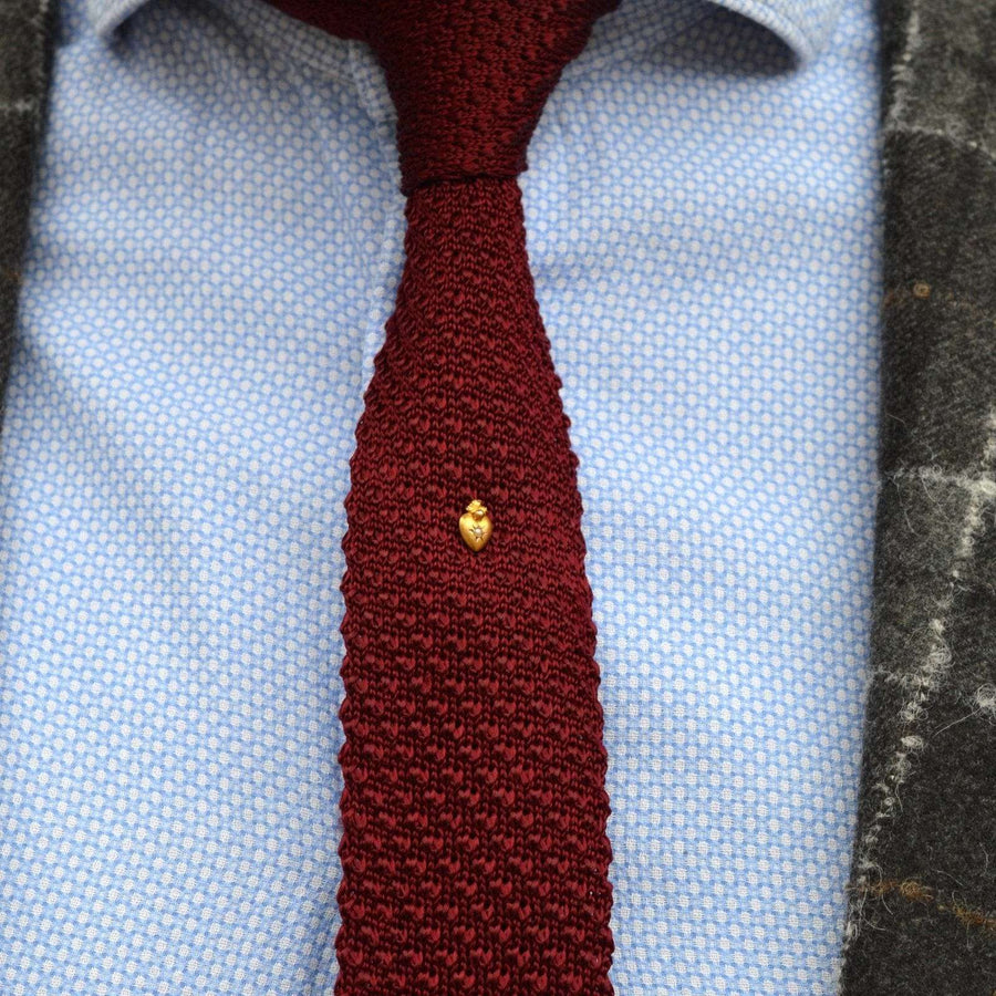 Edwardian 15ct gold burning heart tie pin with pearl on a burgundy tie and blue shirt.