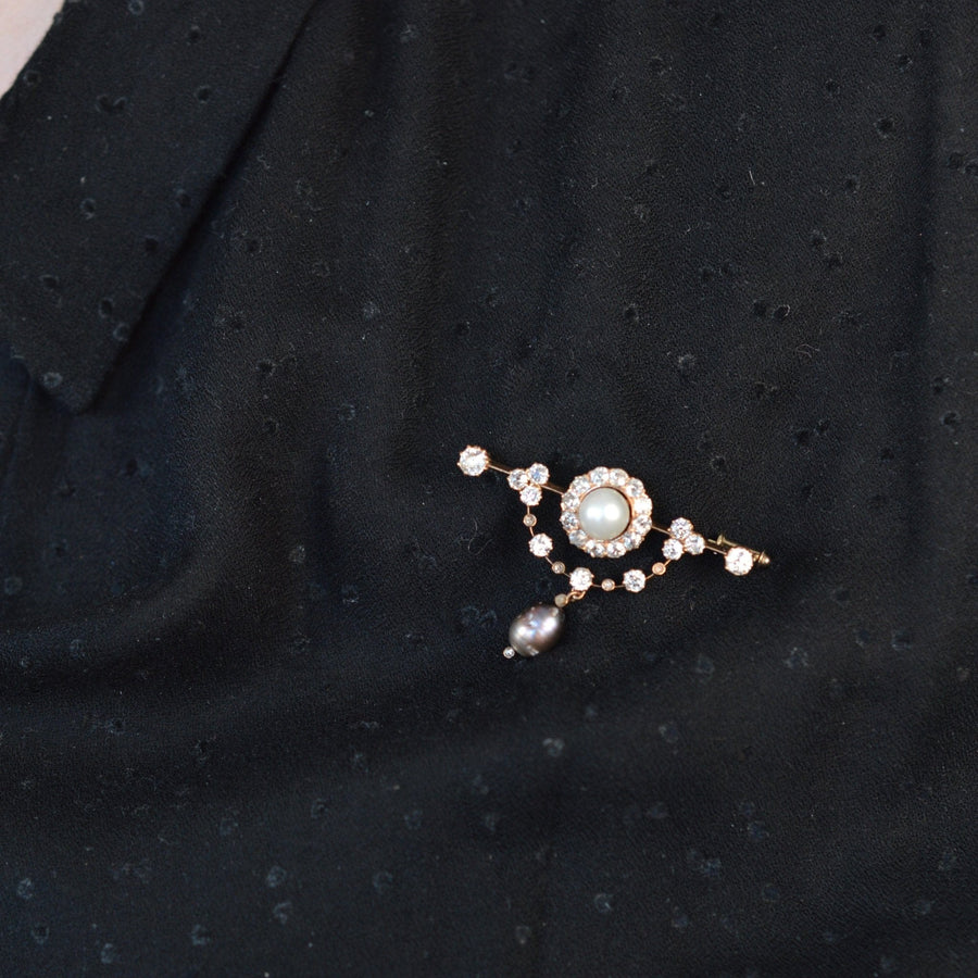 Edwardian 15ct gold bar brooch with diamond, white, and black pearl on black fabric.