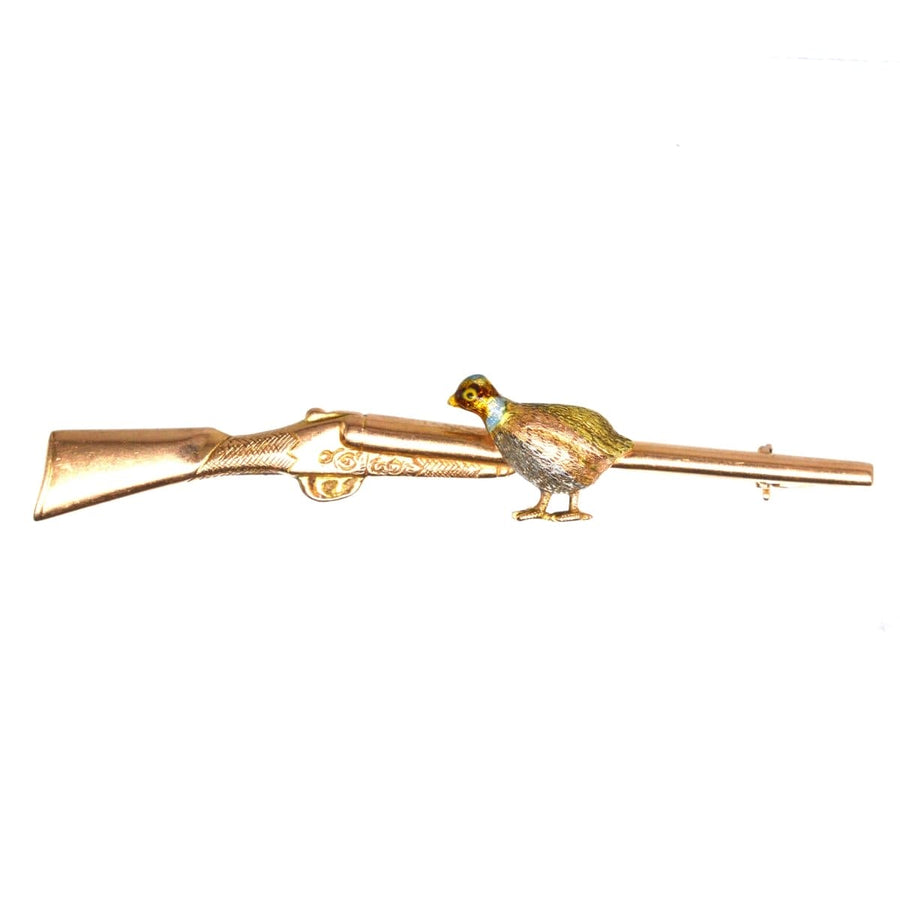 Edwardian gold brooch featuring a grouse perched on a shotgun, showcasing exquisite enamel and platinum details.