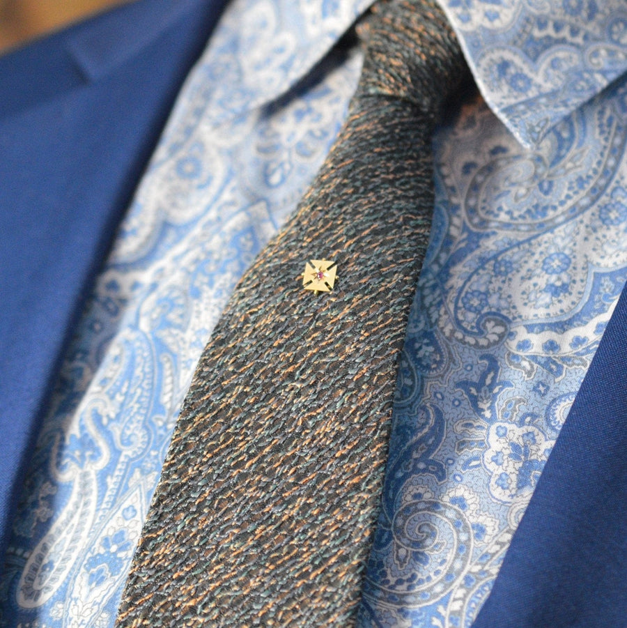 Edwardian 15ct gold Maltese cross tie pin with ruby, worn on a patterned silk tie and dress shirt.