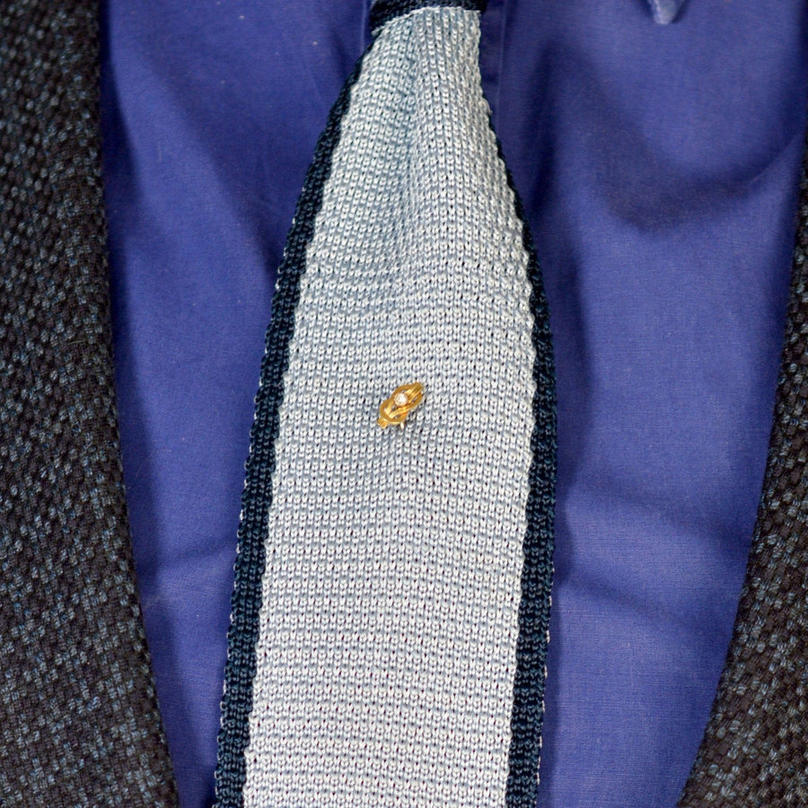 Edwardian 15ct Gold Reef Knot tie pin with diamond on a textured tie, symbolizing love and connection.