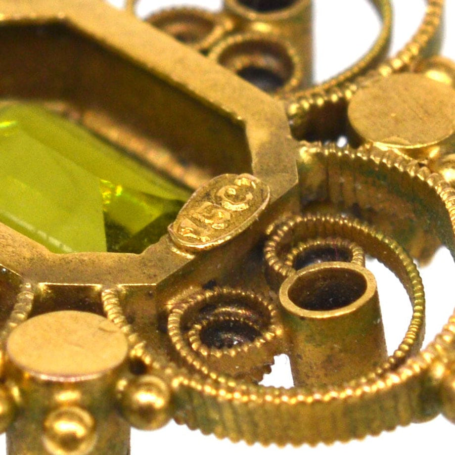 Close-up of a vintage 15ct gold pendant featuring intricate design with green peridot gem.