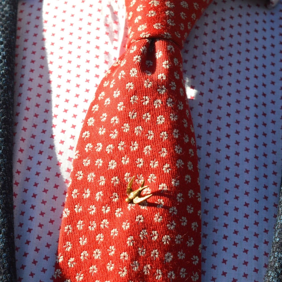 15ct gold swallow tie pin on a red patterned tie, symbolizing love and loyalty.