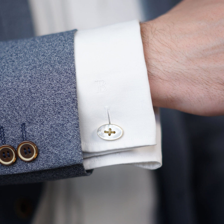 Close-up of a man’s cuff with Edwardian 18ct gold and mother of pearl oval button cufflinks, showcasing elegance.