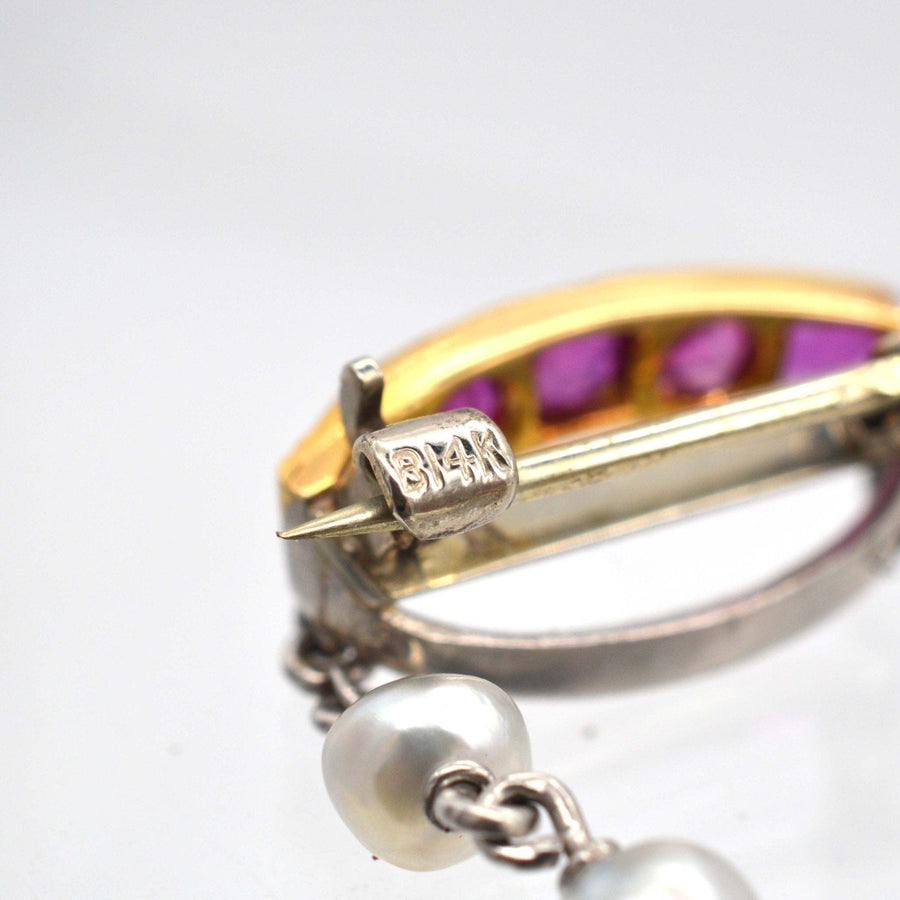 Close-up of Edwardian brooch with gold, platinum, pearls, and ruby accents showcasing intricate design.