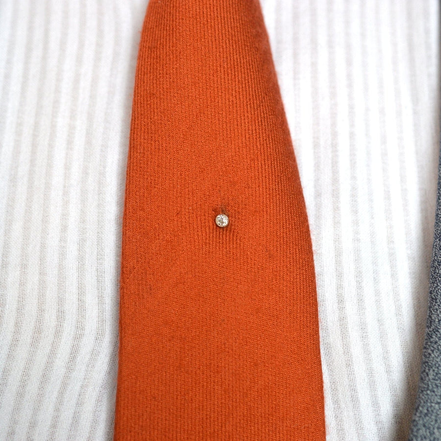 Elegant Edwardian 18ct gold and platinum tie pin featuring a single old European cut diamond on an orange tie.