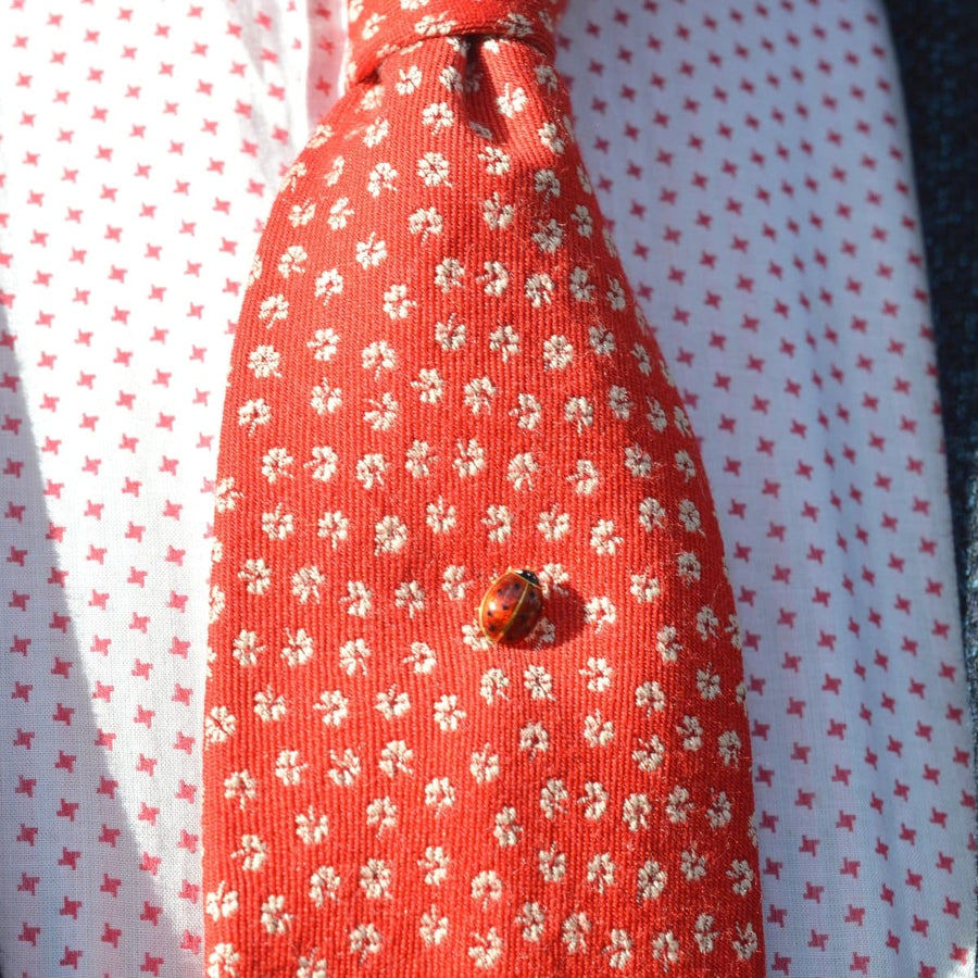 18ct gold and enamel ladybird tie pin on a vibrant red patterned silk tie, perfect for special occasions.