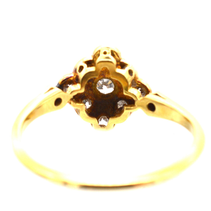 Edwardian 18ct gold diamond cluster ring with elegant shoulders and a low-profile design.