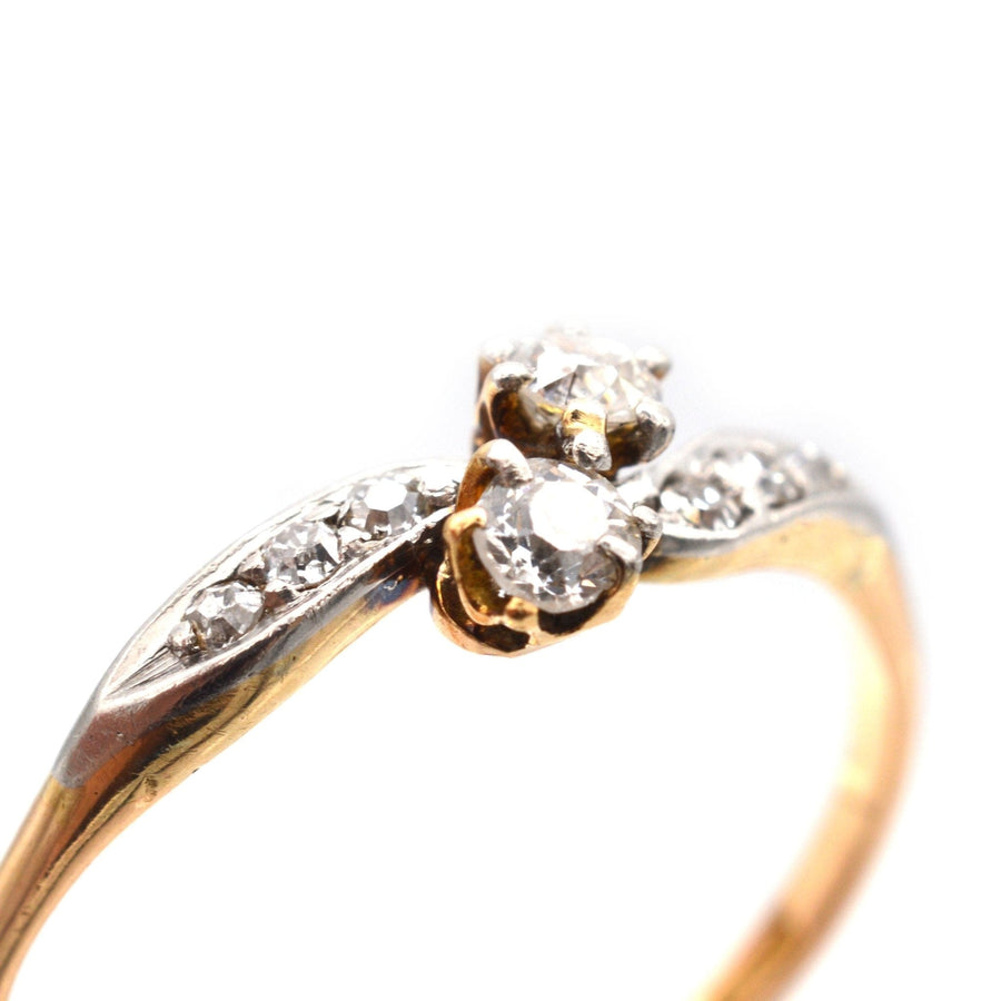 Edwardian 18ct gold and platinum crossover ring with two diamonds and diamond shoulders, elegant design.