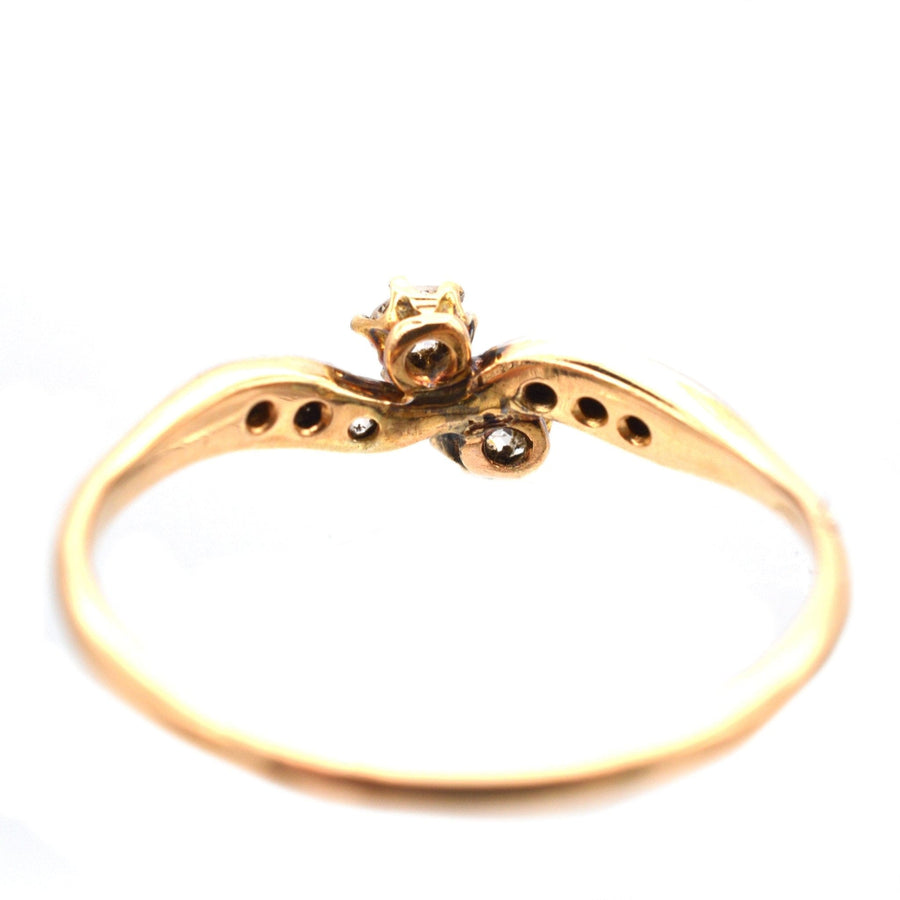 Edwardian gold and platinum two stone crossover ring featuring diamond shoulders, perfect for romantic occasions.
