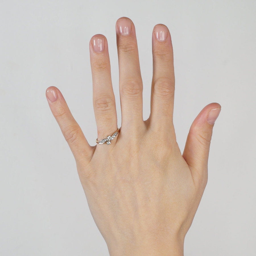 Elegant hand wearing an Edwardian two stone diamond crossover ring with diamond shoulders, showcasing its romantic design.