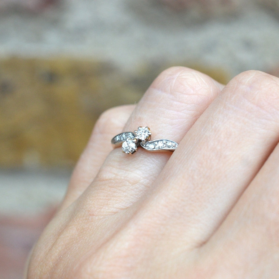 Edwardian two stone diamond crossover ring in 18ct gold and platinum, displayed on a hand.
