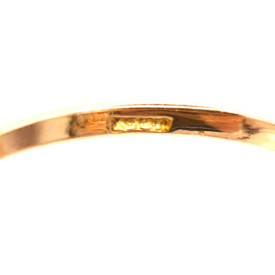 Close-up of the inner band of an 18ct gold ring showing hallmark details.