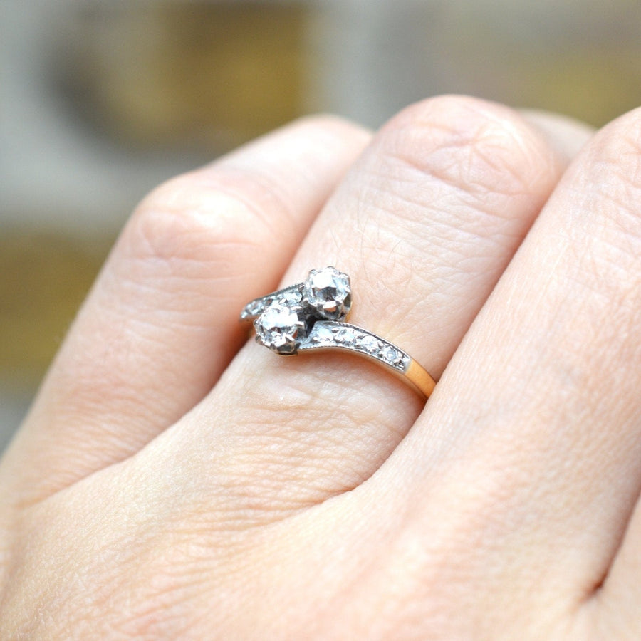 Elegant Edwardian 18ct gold and platinum two stone diamond 'Toi et Moi' crossover ring on a finger.