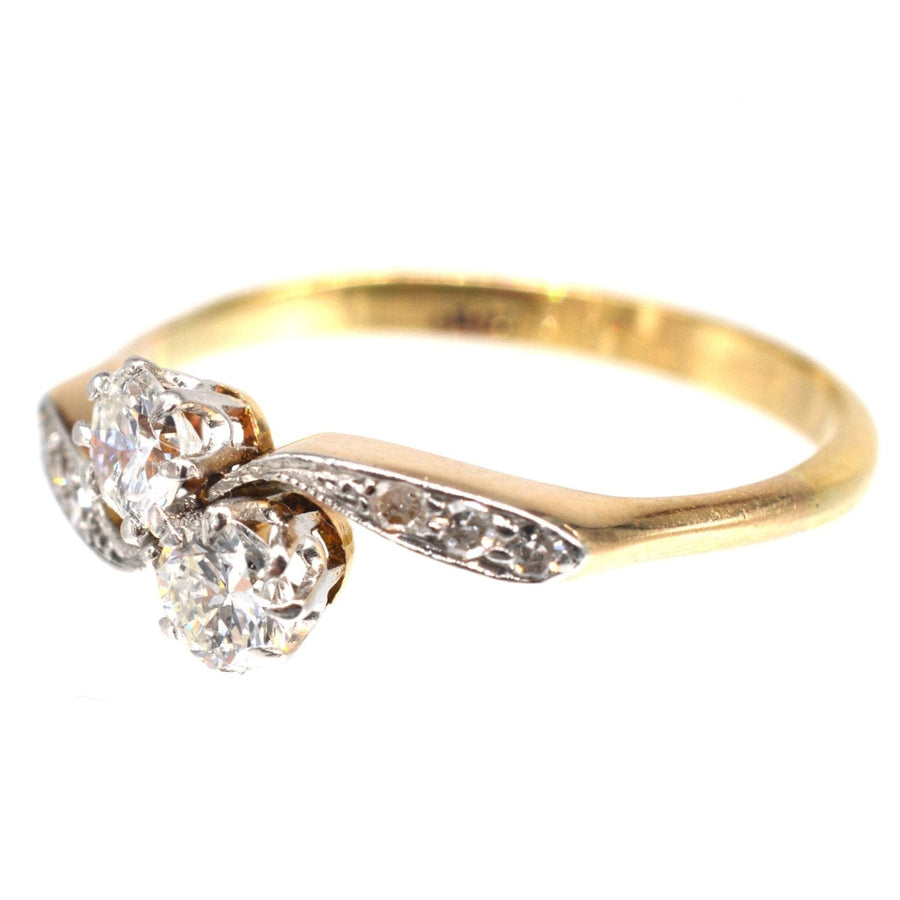 Edwardian gold and platinum 'Toi et Moi' crossover ring featuring two diamonds and diamond shoulders.