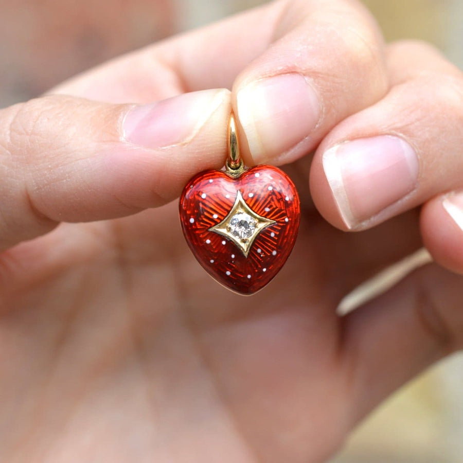 Edwardian 18ct gold red enamel heart locket pendant with diamond, held in hand, showcasing unique design.