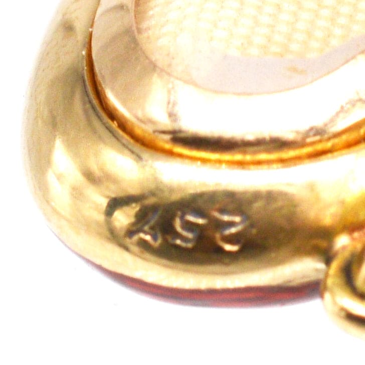 Close-up of Edwardian 18ct gold locket showing hallmark detail and rich red enamel finish.