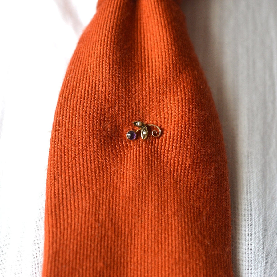 Edwardian 9ct gold tie pin featuring amethyst and seed pearl design on an orange tie, complete with stoppers.